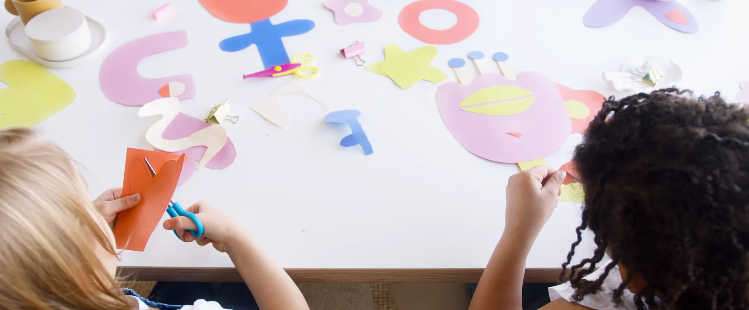 Two young girls are making paper letters on a wall